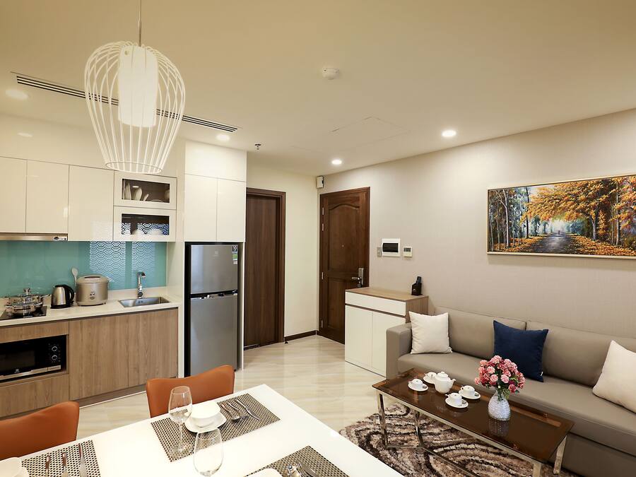 Un apartamento moderno con cocina, comedor y sala de estar. Cuenta con refrigerador, microondas y mesa de comedor con sillas.