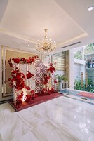 Un área de recepción con una araña, un arreglo floral rojo y un suelo de mármol.