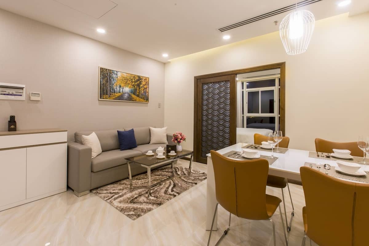 A modern living room with a sofa, coffee table, and dining area with chairs and a table set for a meal.