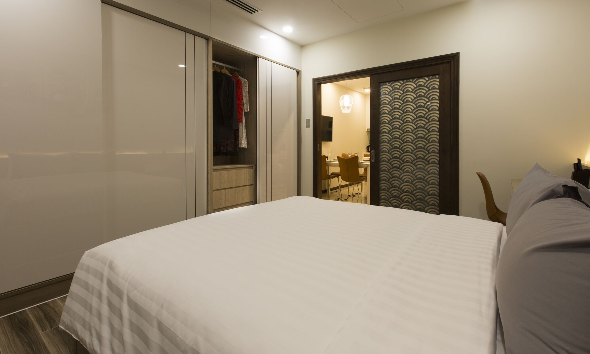 Habitación de hotel con cama, armario, baño con espejo y zona de comedor.