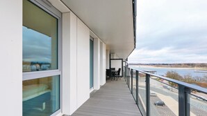 Un balcon donnant sur une rivière et sur des bâtiments situés au loin.