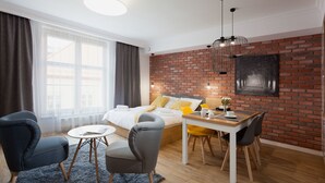 Une chambre moderne avec un mur en briques, un grand lit avec une literie blanche, une table à manger avec des chaises, et une vue sur la ville par la fenêtre.