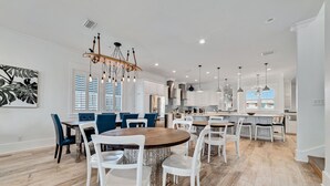 Een moderne keuken met witte kastjes, een centraal eiland en hangende lampen.