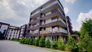 A multi-story residential building with balconies and a landscaped area with small trees. - City of the Kings Green Silence Apartment (Kraków)