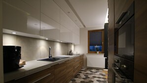 A modern kitchen with a wooden countertop, built-in cabinets, a sink, and a window with a view. - City of the Kings Green Silence Apartment (Kraków)