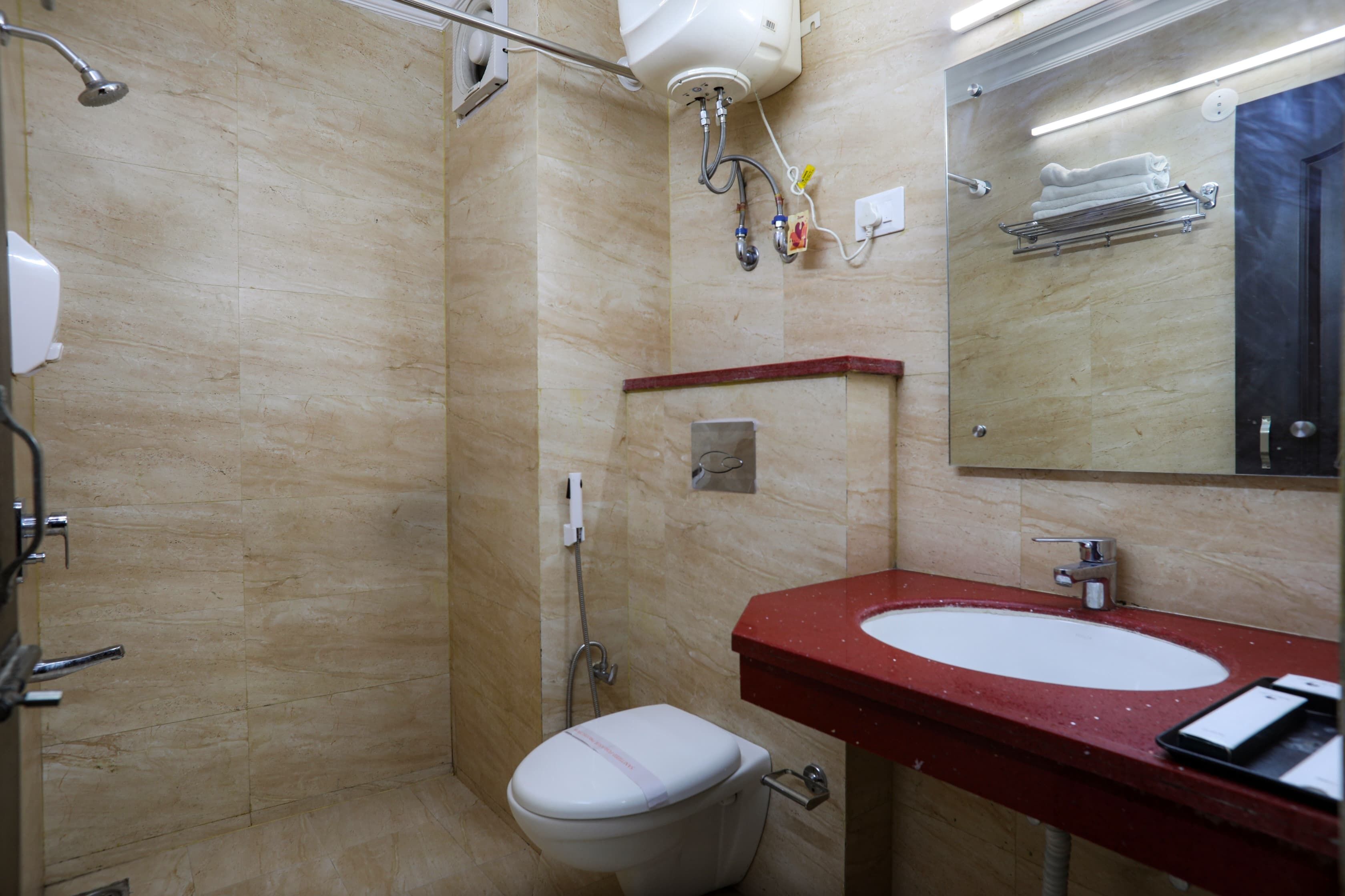 A bathroom with a white toilet, a red sink, and a mirror above the sink.