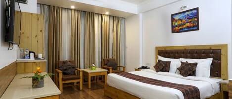 A hotel room with a large bed, a desk, a chair, a television, and a painting on the wall.