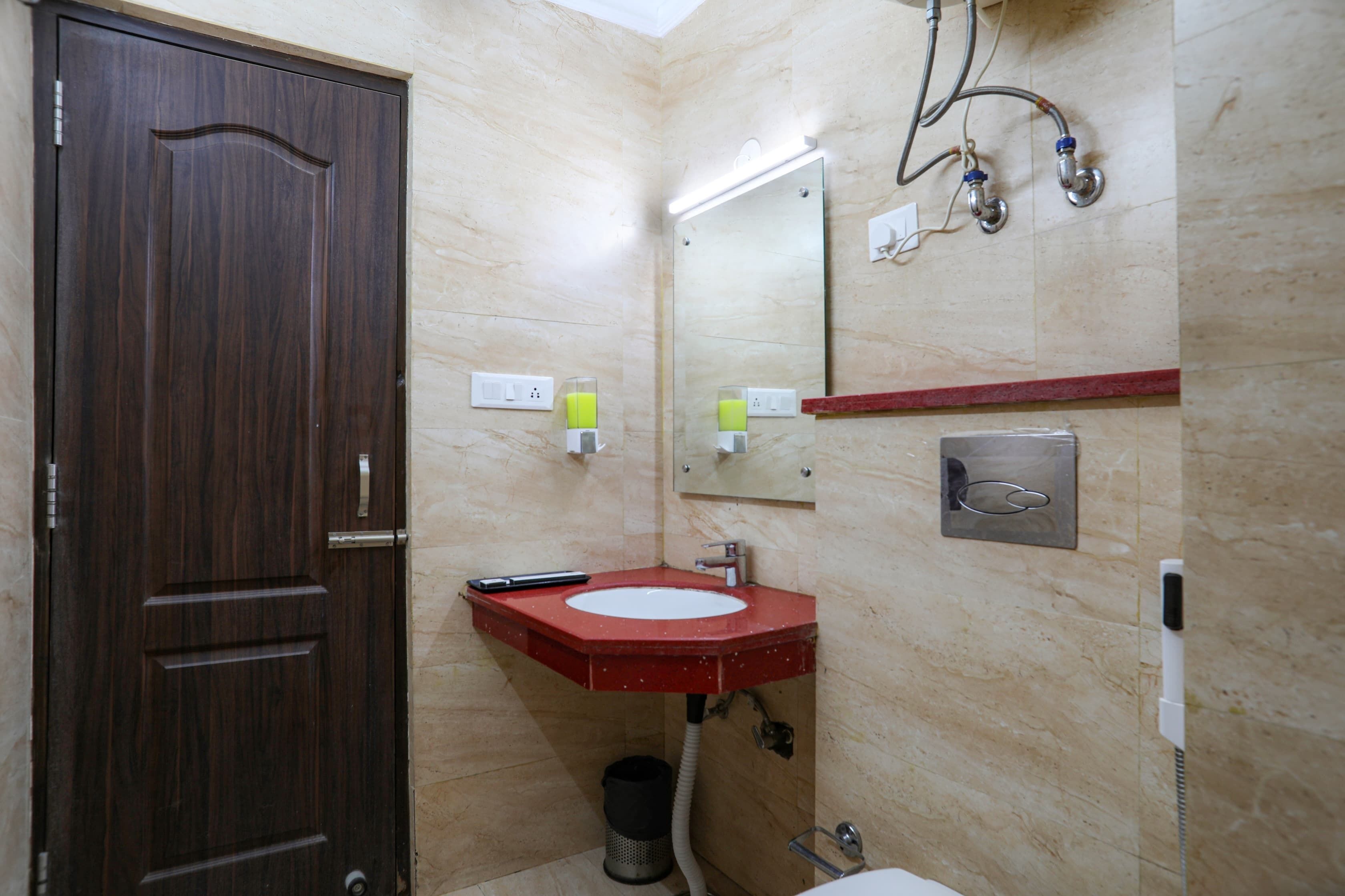 Une salle de bain avec une porte en bois, un lavabo rouge, un miroir et un porte-serviettes.