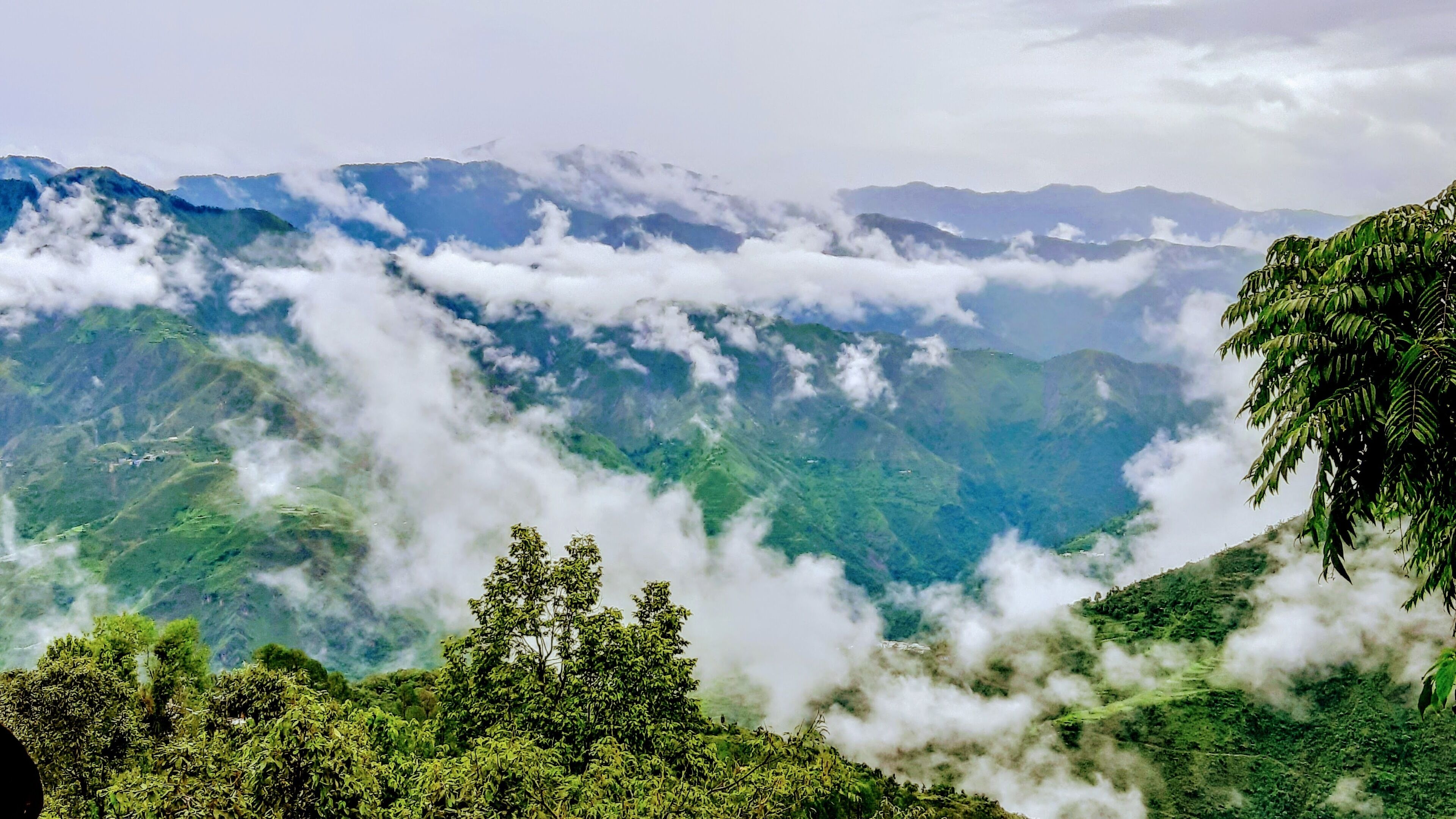 A mountainous landscape with lush greenery and clouds.