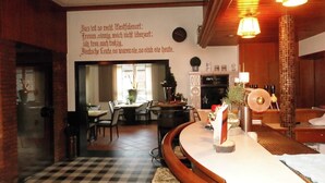 A restaurant with a checkered floor, wooden furniture, and a wall with a German text. - Landgasthaus Hotel Eggert (Rheine)