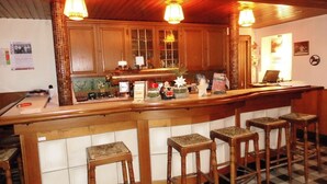 A bar area with wooden stools, a counter, and a tiled floor. - Landgasthaus Hotel Eggert (Rheine)