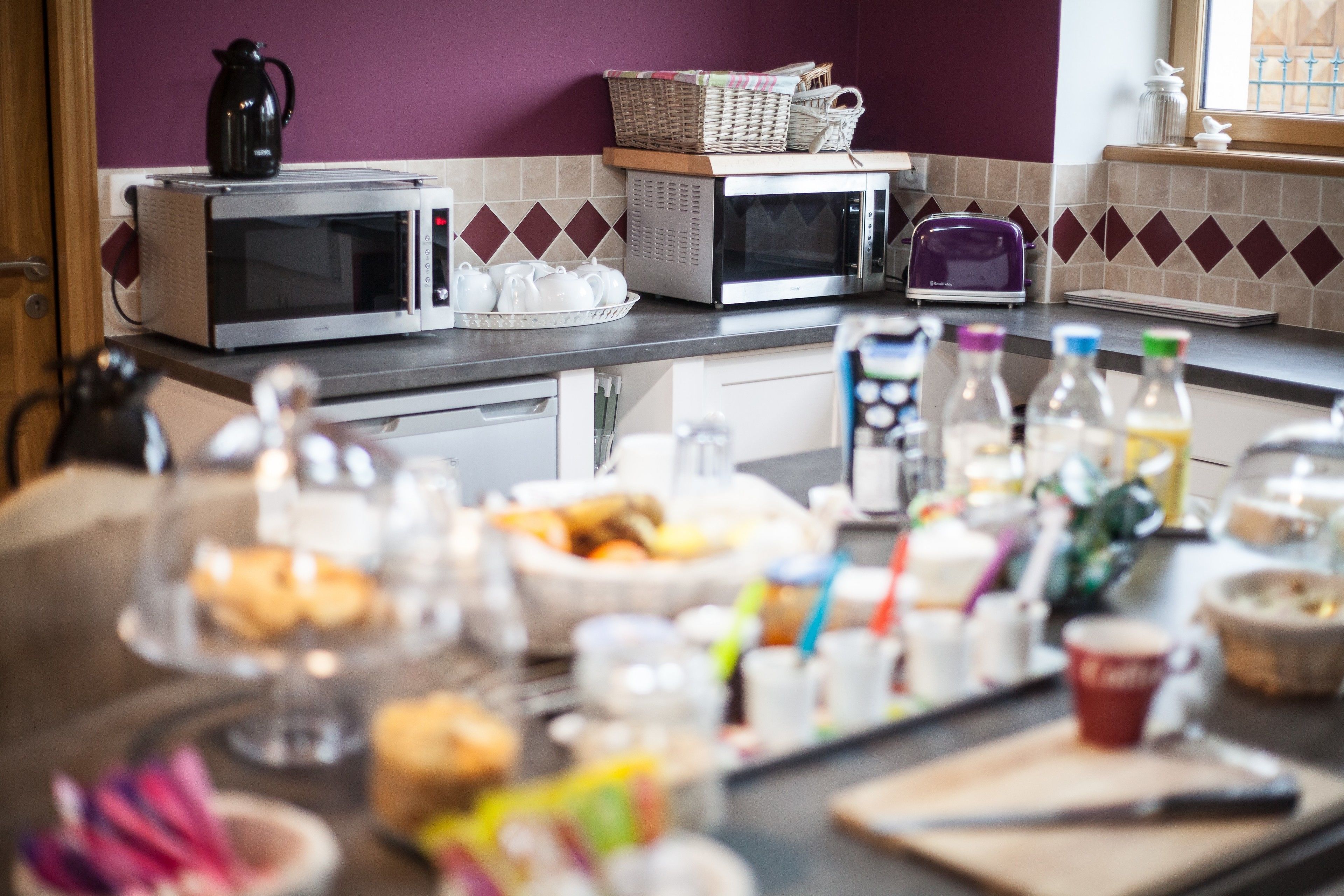 A kitchen with two microwaves, a toaster, and various kitchen items on the counter.