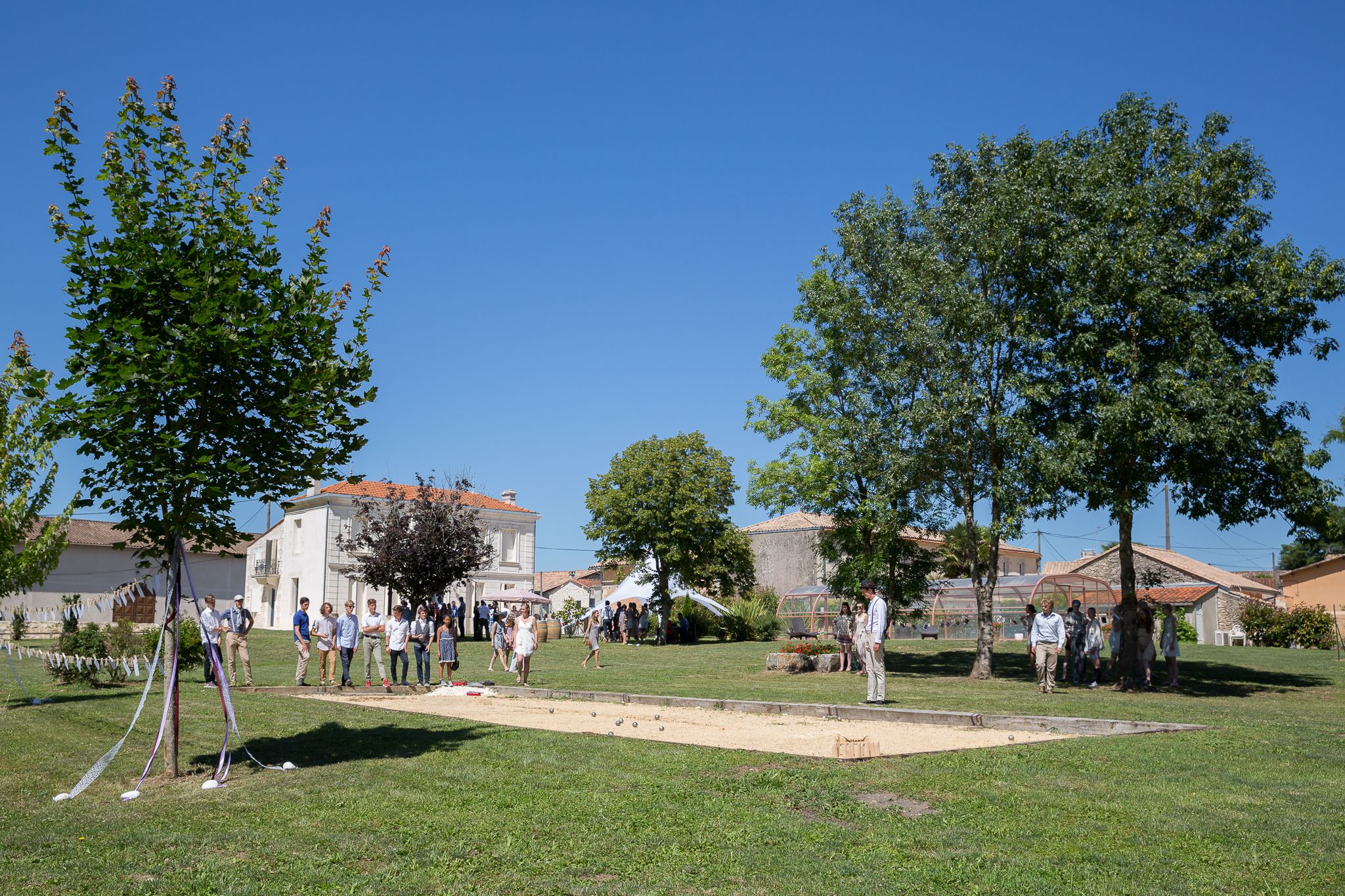 A courtyard with a lawn, trees, and a building with a red-tiled roof.