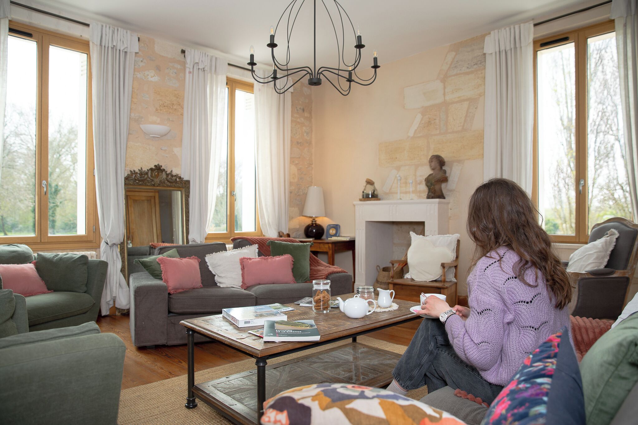 A cozy living room with a fireplace, comfortable seating, and a coffee table with books and a teapot.