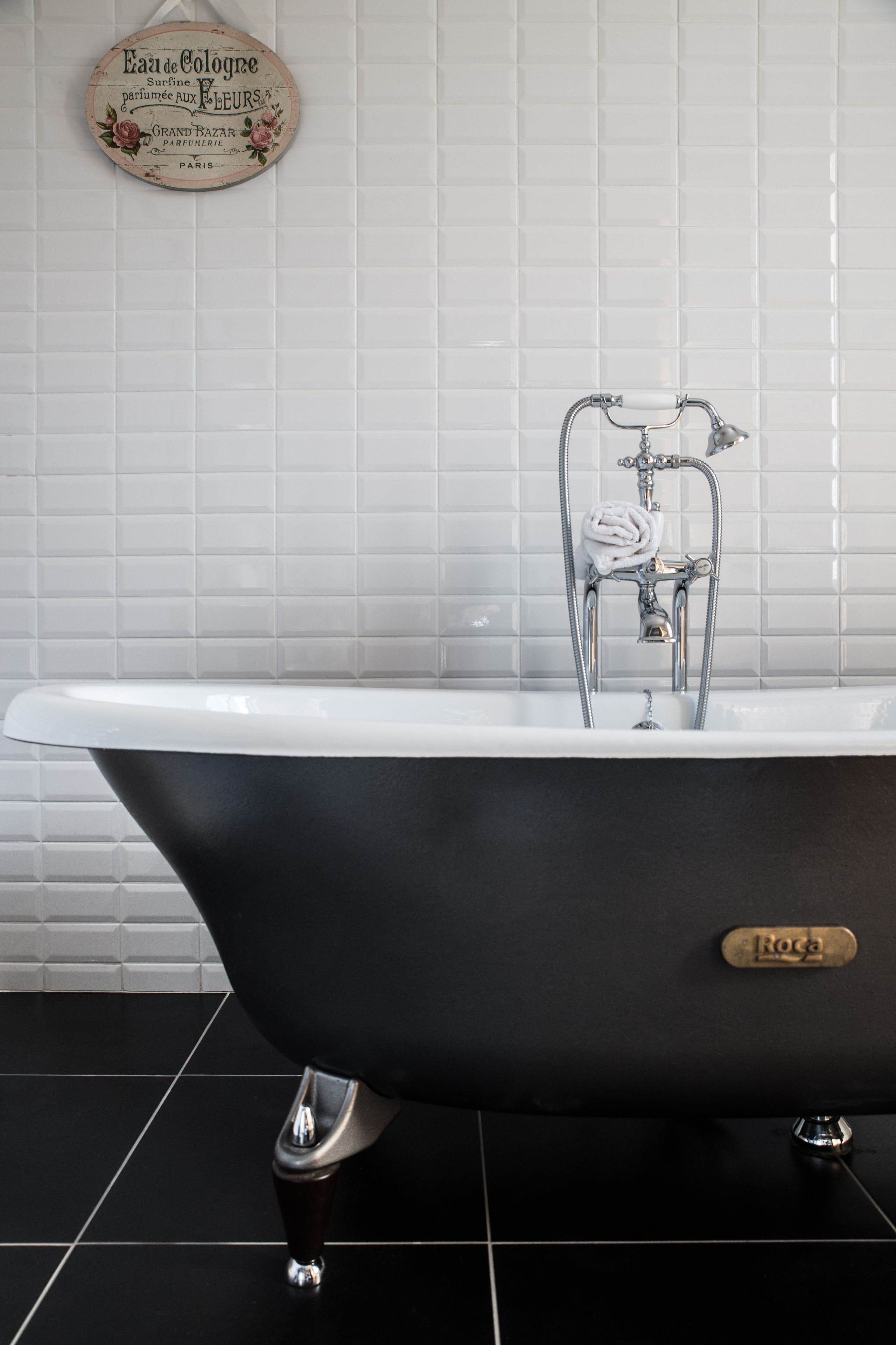 A black bathtub with a showerhead and a towel.