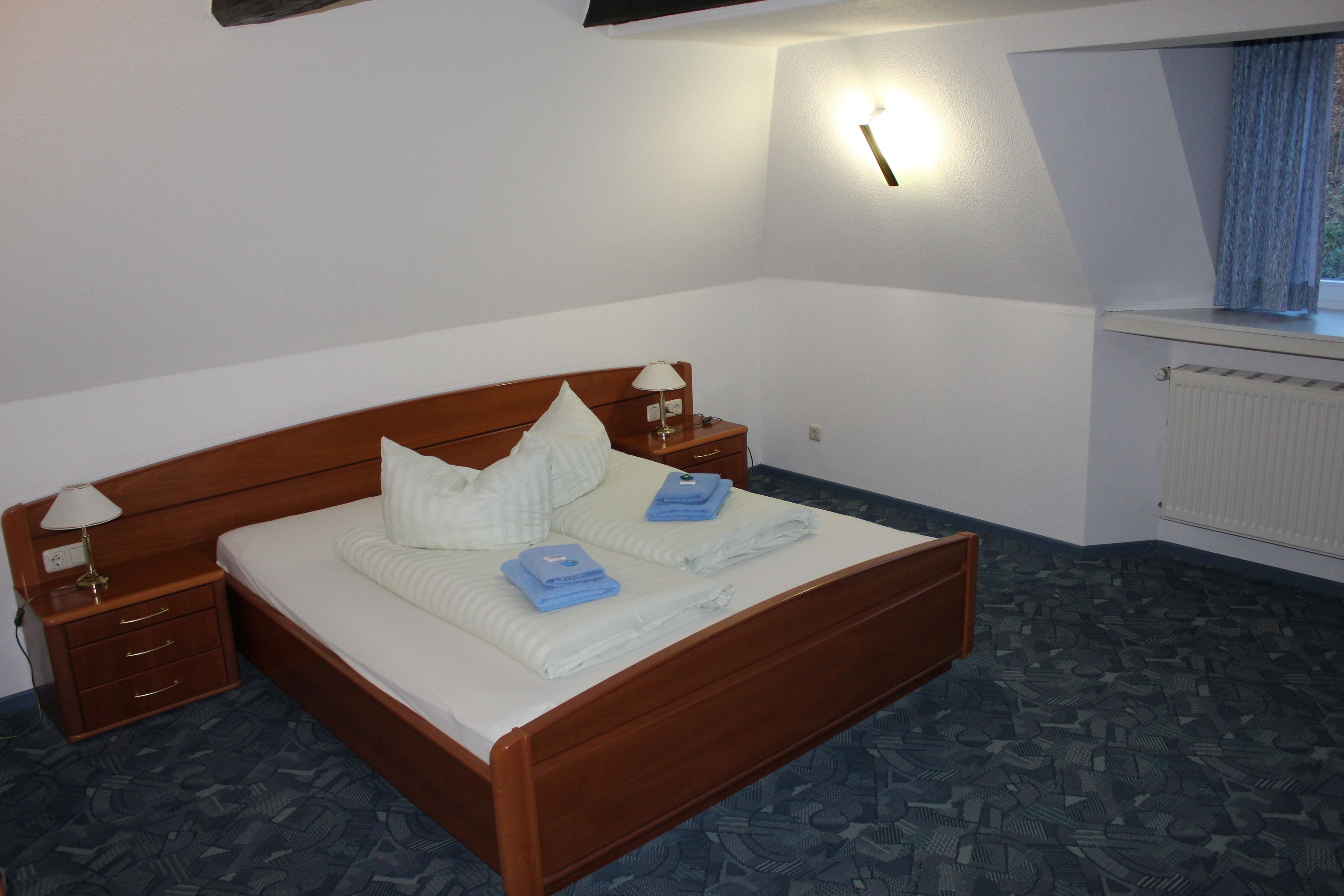 Une chambre à coucher avec un lit en bois, une table de chevet, une lampe et un luminaire fixé au mur.
