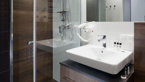 A modern bathroom with a glass-enclosed shower, a white sink, and a mirror above it. - City of the Kings City Point Apartments (Kraków)