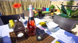 An outdoor dining area with a table set for two, featuring a bottle, a candle, and a small decorative item. - Apartment Emelia (Paphos)