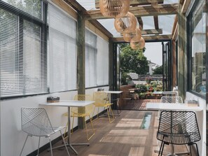 A modern outdoor seating area with metal and wicker chairs, wooden tables, and a view of the garden. - Suzhou Cloud Art Inn (Suzhou)