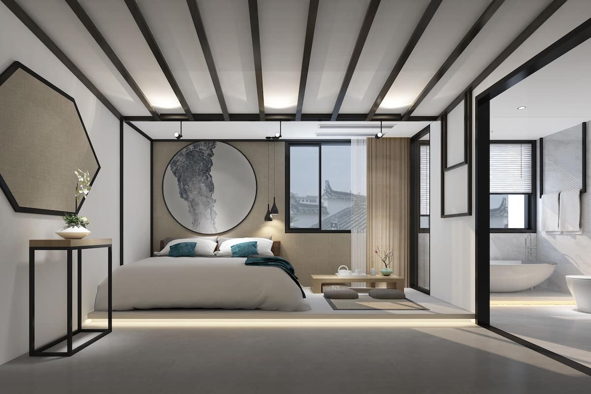 Une chambre moderne avec un grand lit, un miroir rond et une vue sur une architecture traditionnelle, visible à travers une fenêtre.