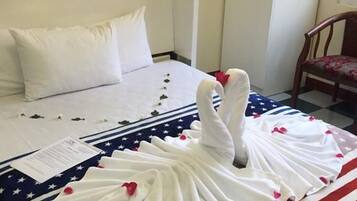 Ein Hotelzimmer mit einem ordentlich bezogenem Bett, einem gerahmten Bild an der Wand und einem Holzstuhl.