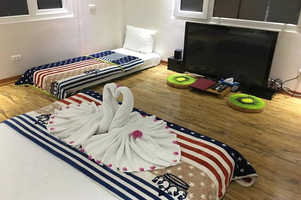 Una habitació amb dos llits, televisió i finestra.