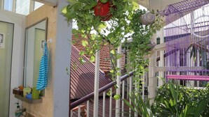 A balcony with a metal railing, a red hanging pot, and a purple birdcage. - An Family Homestay (Hanoi)