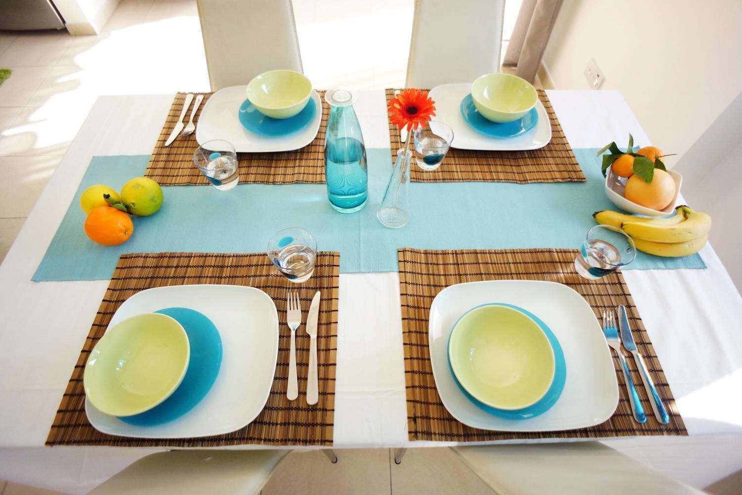 A dining table set with blue and white plates, cutlery, and a blue water bottle.