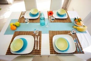 A dining table set with blue and white plates, cutlery, and a blue water bottle.