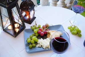 A table with a plate of cheese and grapes, a glass of red wine, and two decorative lanterns. - Apartment Sinogi (Paphos)