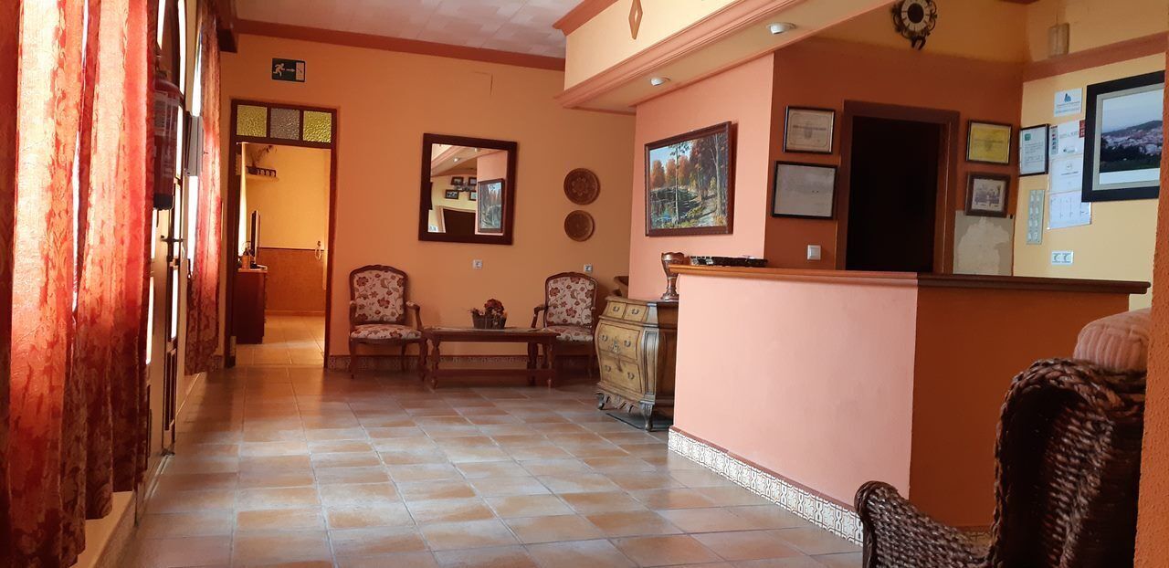 A reception area with a counter, two armchairs, a bench, and a wall with framed pictures and certificates.