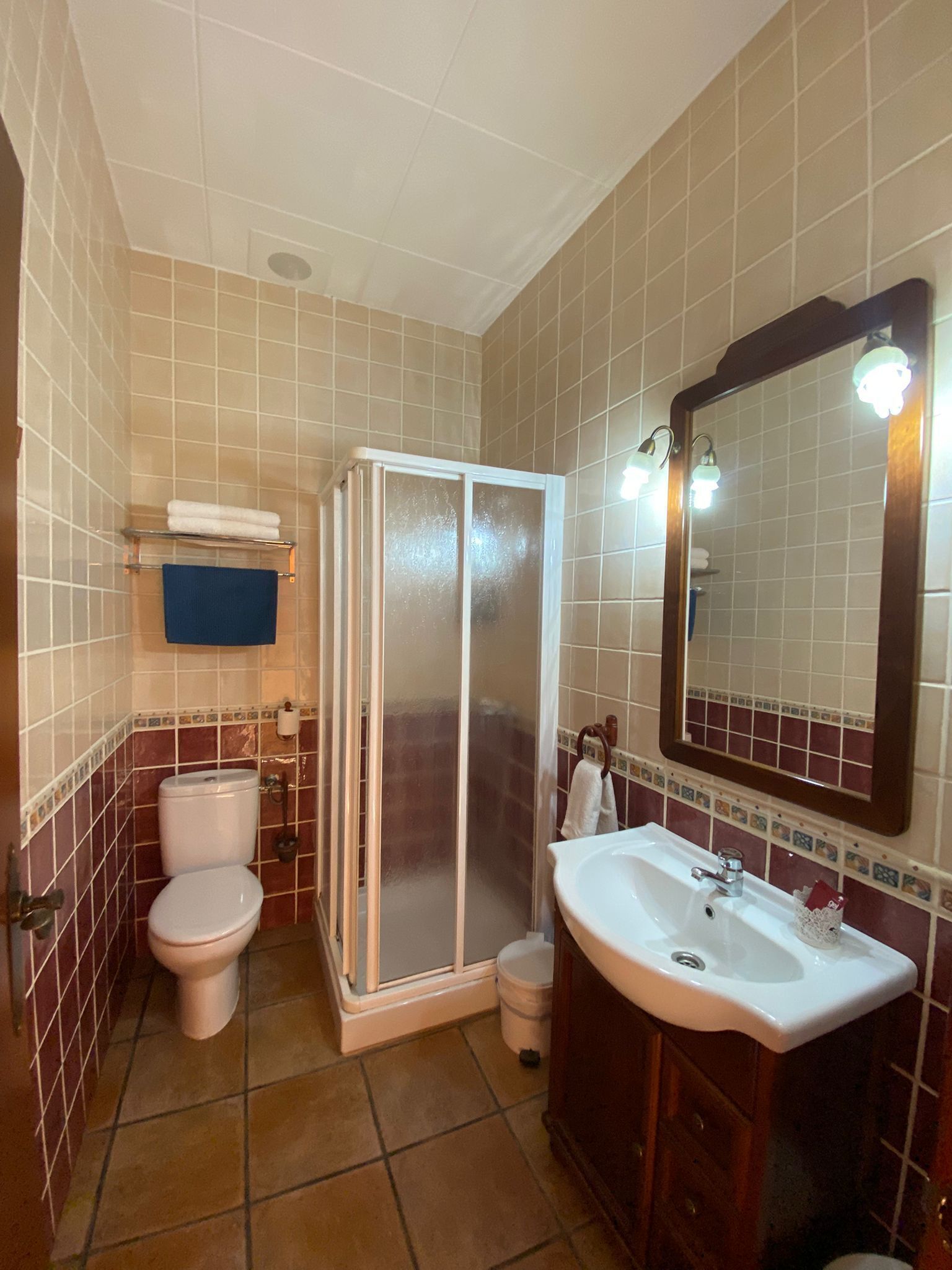 Un baño con inodoro, cabina de ducha, lavabo y espejo.