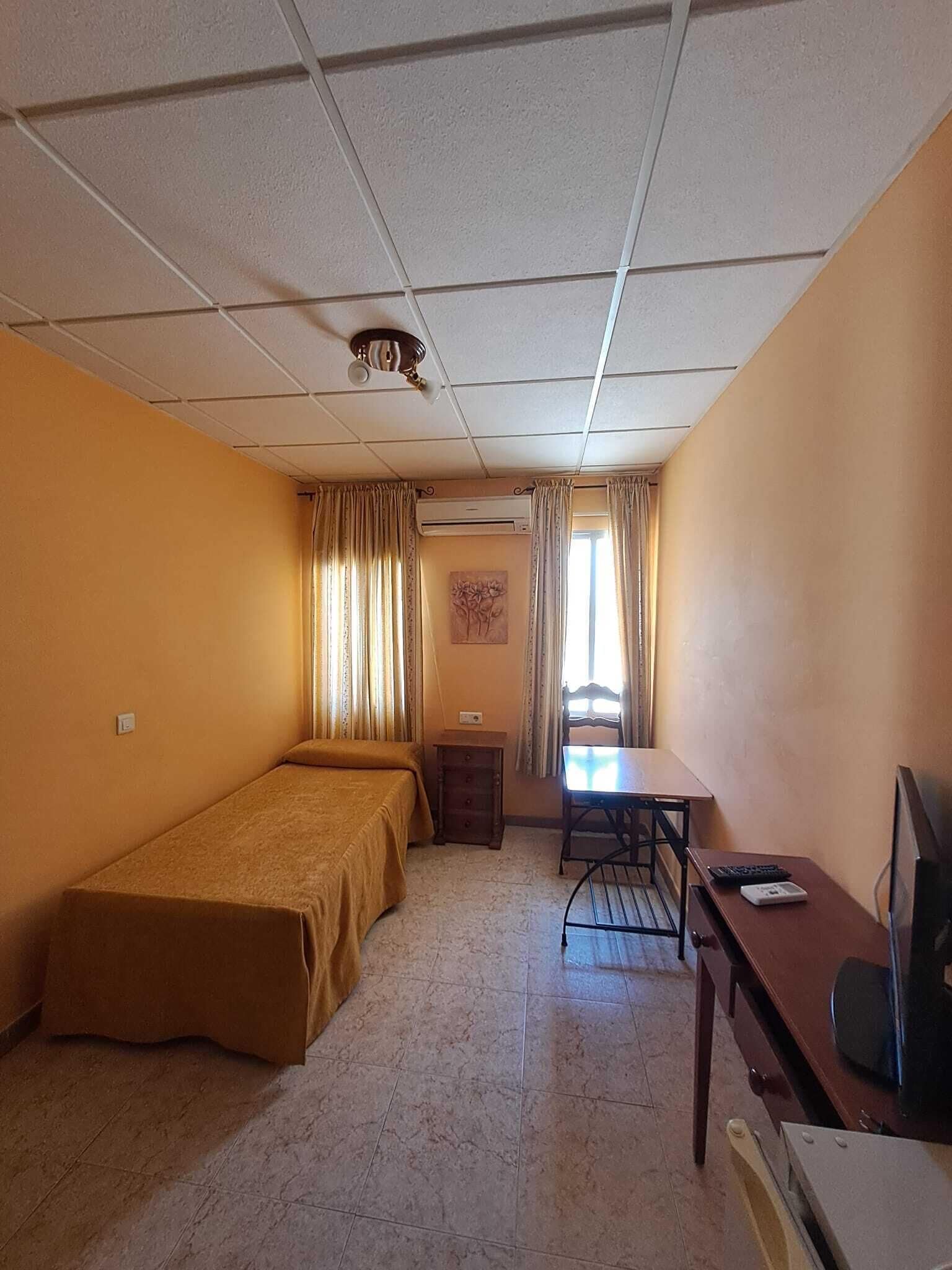 Hotellihuone, jossa on sänky, työpöytä, tuoli ja televisio.