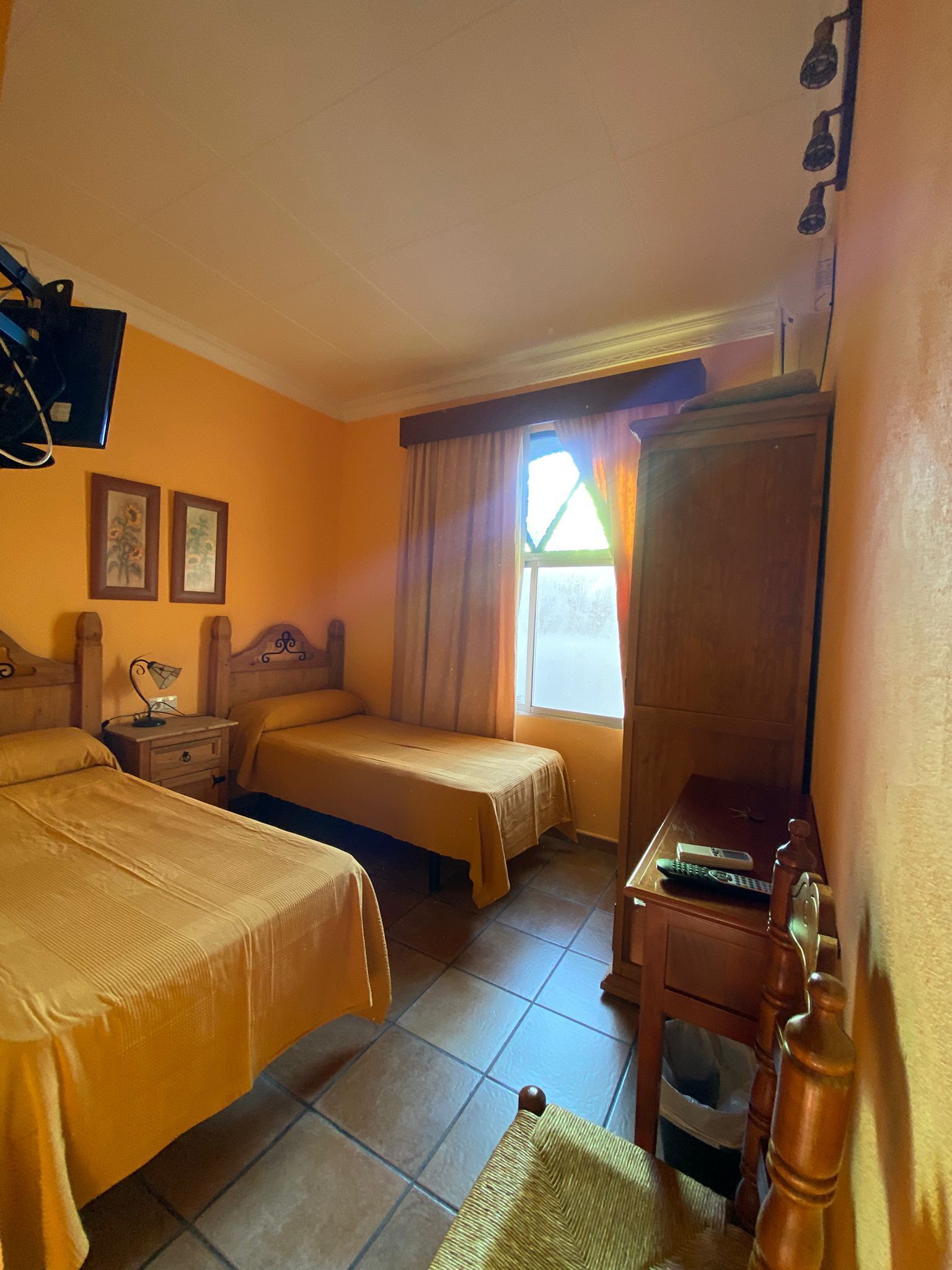 A hotel room with two beds, a desk, a chair, a TV, and a window with curtains.