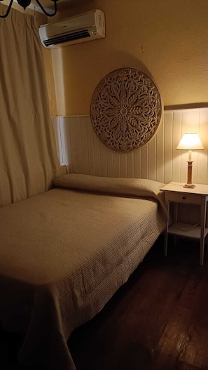 Une chambre comprenant un lit, un climatiseur fixé au mur, un élément décoratif mural et une lampe de chevet.
