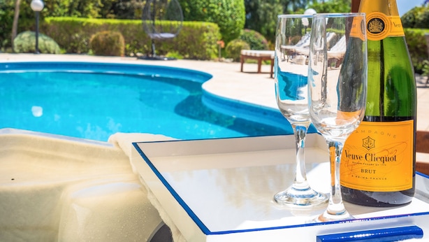 A bottle of Veuve Clicquot champagne, two glasses, and a tray with a poolside view. - Villa Atlantica (Pegeia)