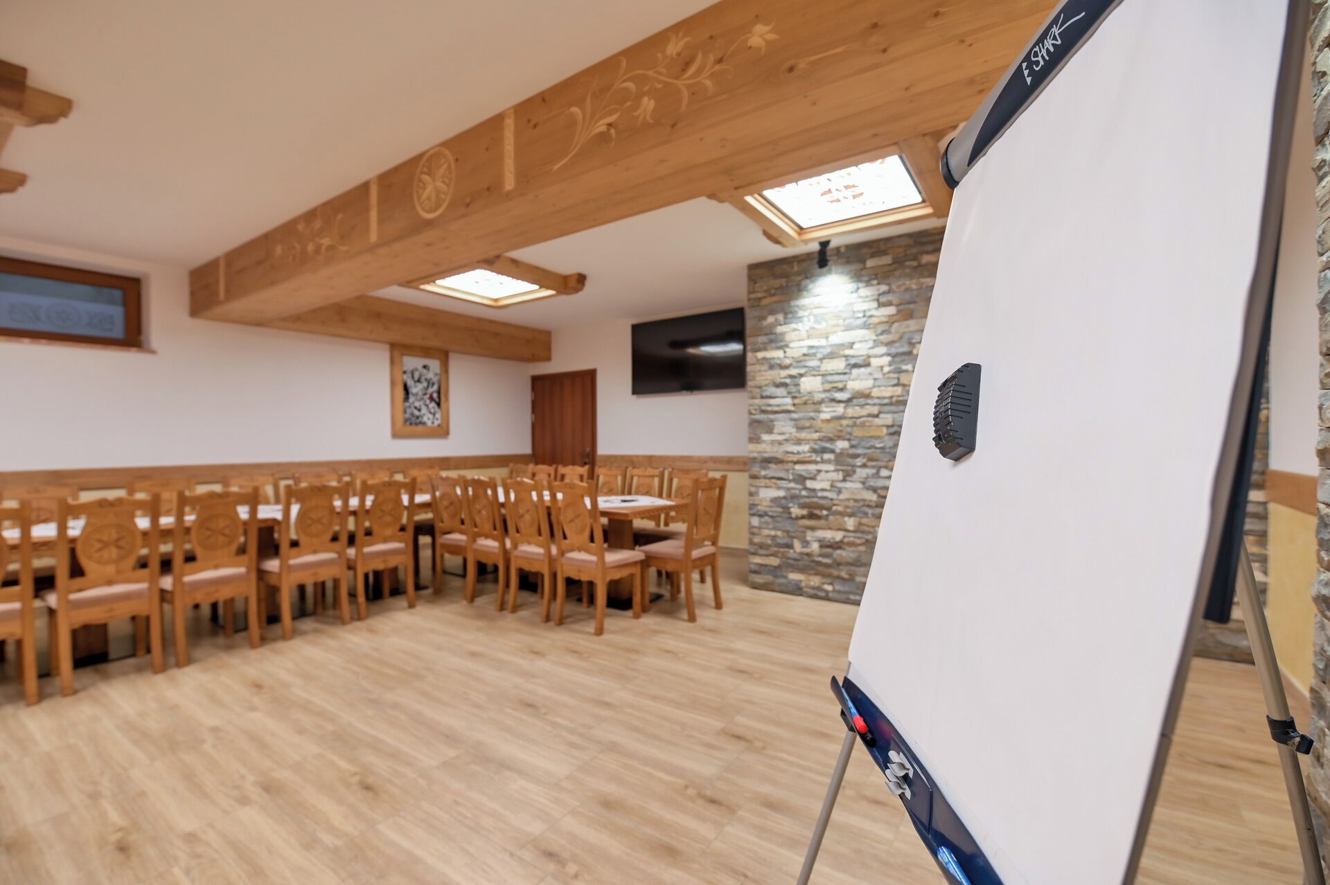 A conference room with wooden chairs and tables, a whiteboard, and a stone wall.