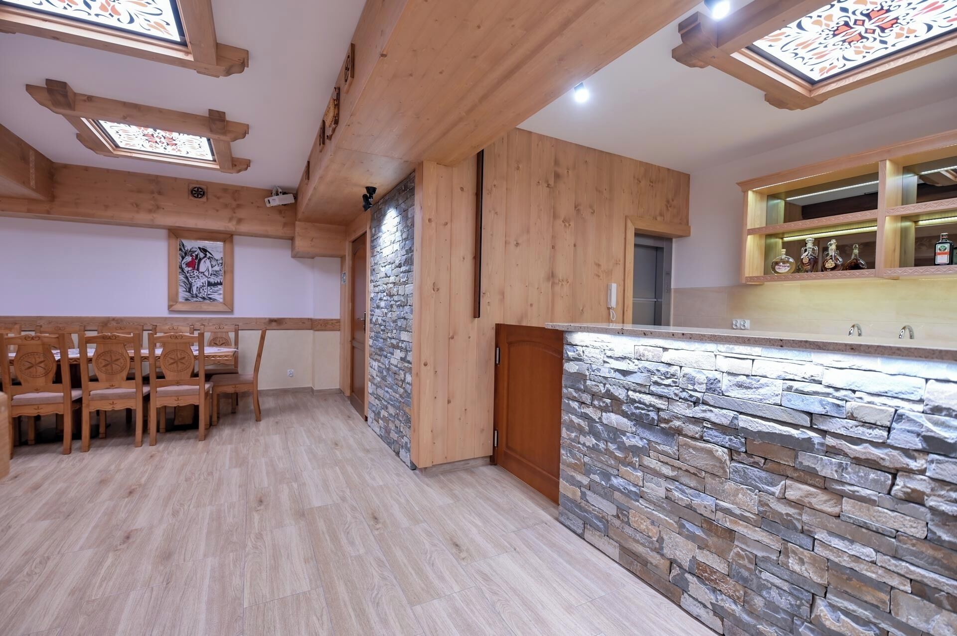 A modern kitchen with a stone backsplash, wooden cabinets, and a dining area with chairs.