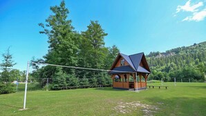 A wooden cabin with a sloped roof, surrounded by a grassy field and trees. - Pod Tatrami (Bukowina Tatrzanska)