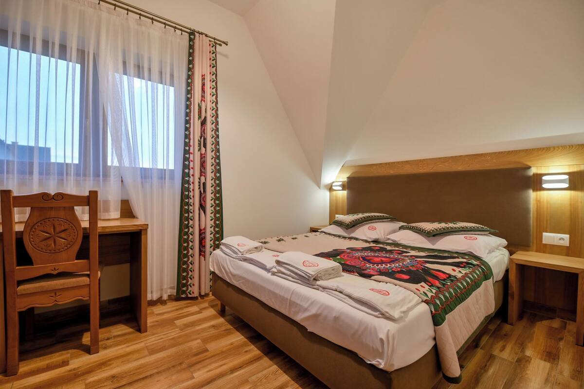 Un dormitorio con cama de madera, un escritorio y una silla.
