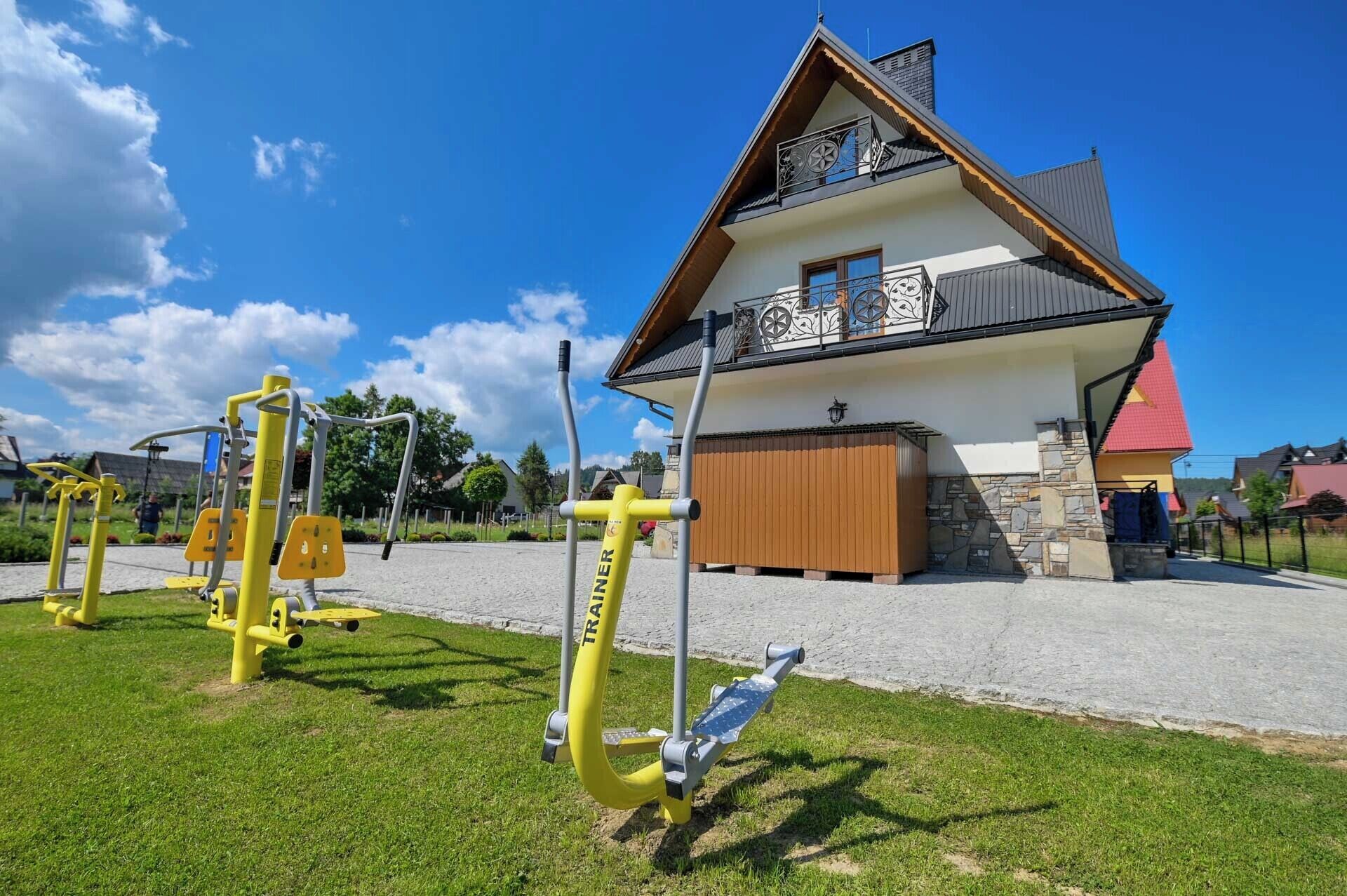 A house with a stone foundation, a balcony with metal railings, and a red roof.