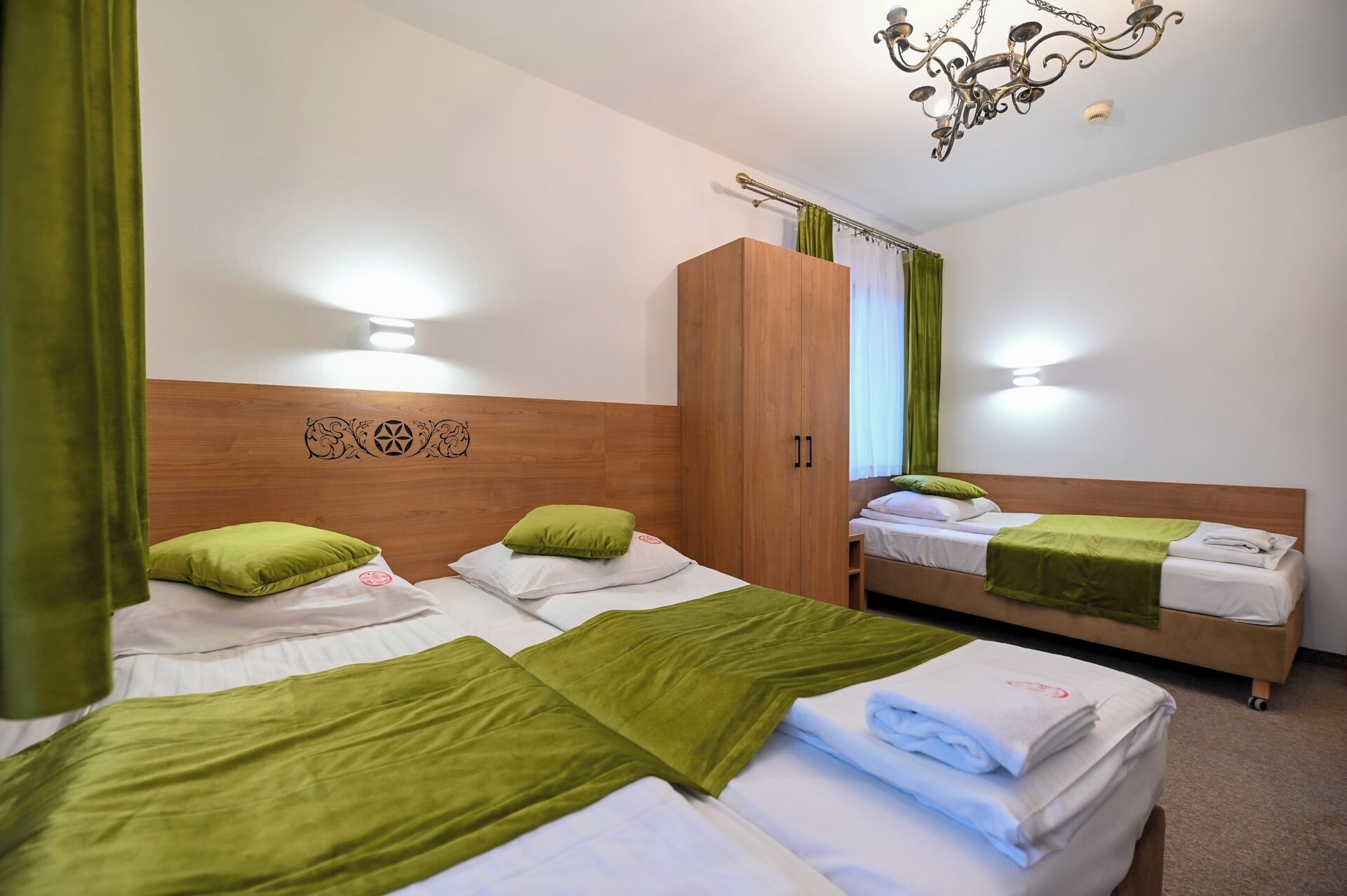 A hotel room with two beds, a wardrobe, and a chandelier.
