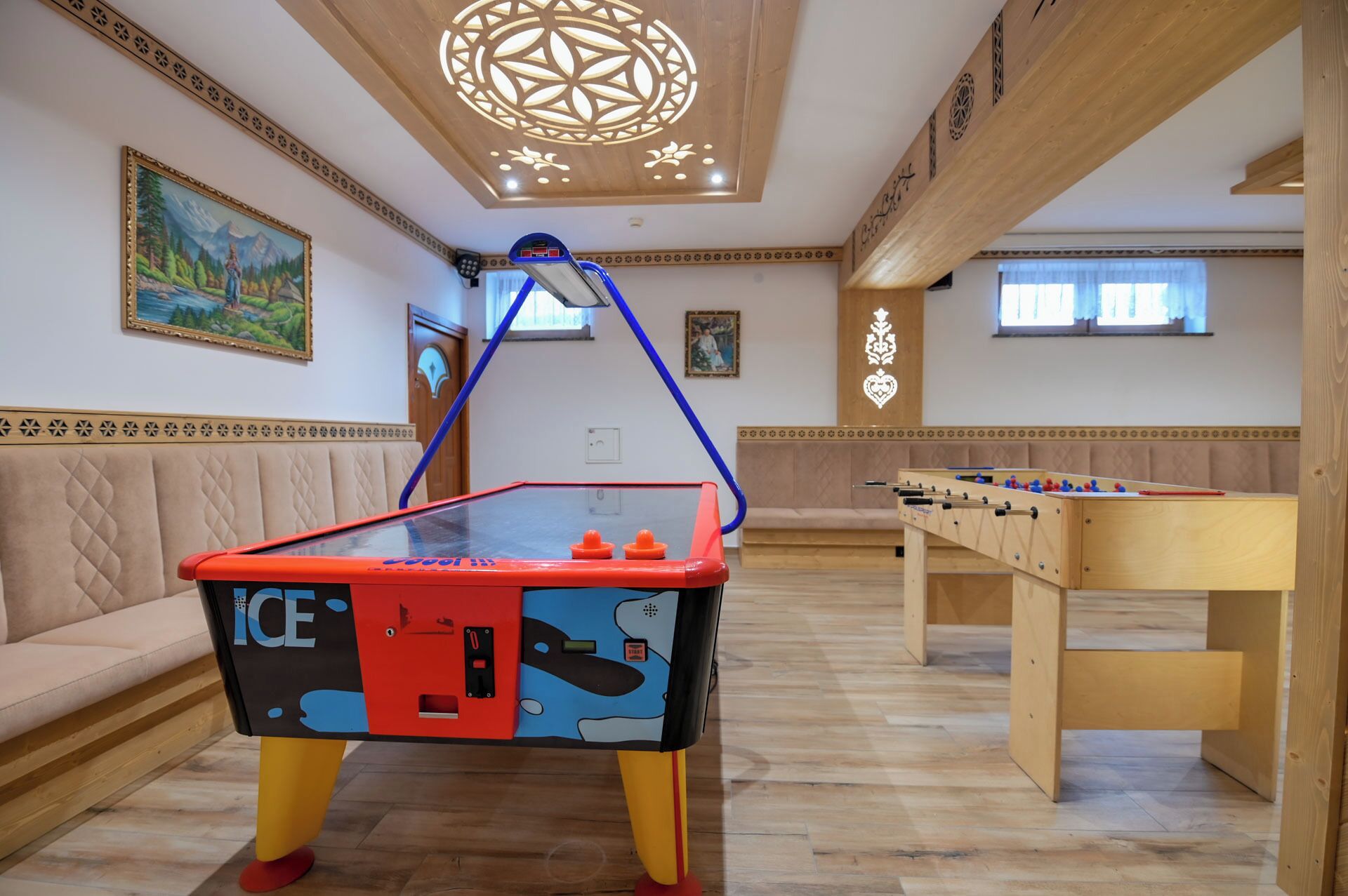 A room with a foosball table, a table tennis table, and a sofa.
