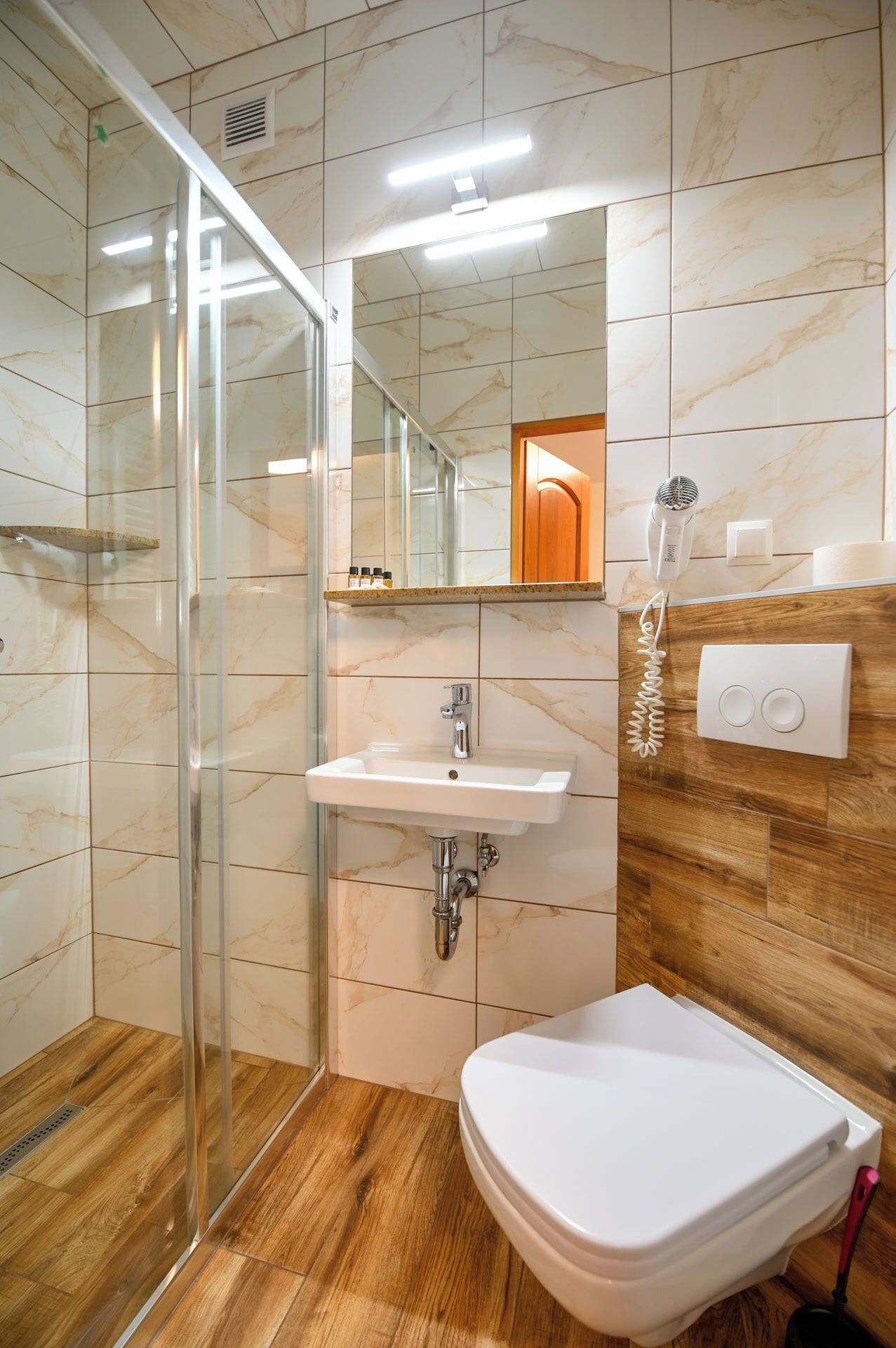 Une salle de bain moderne avec une douche à parois de verre, un lavabo, des toilettes et un sèche-cheveux.