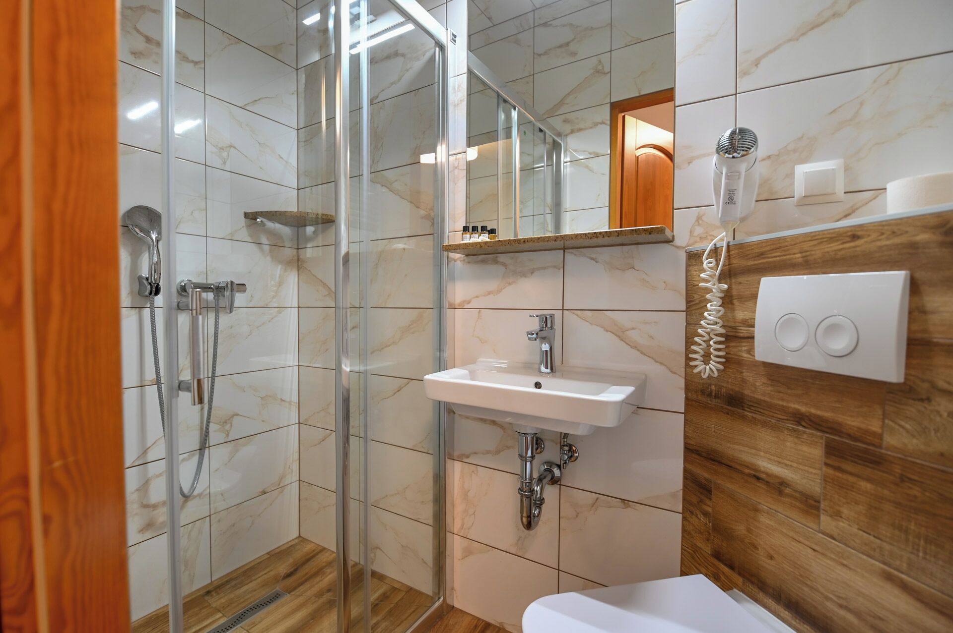 Une salle de bain moderne avec une douche à parois de verre, un lavabo blanc et un meuble-lavabo en bois.