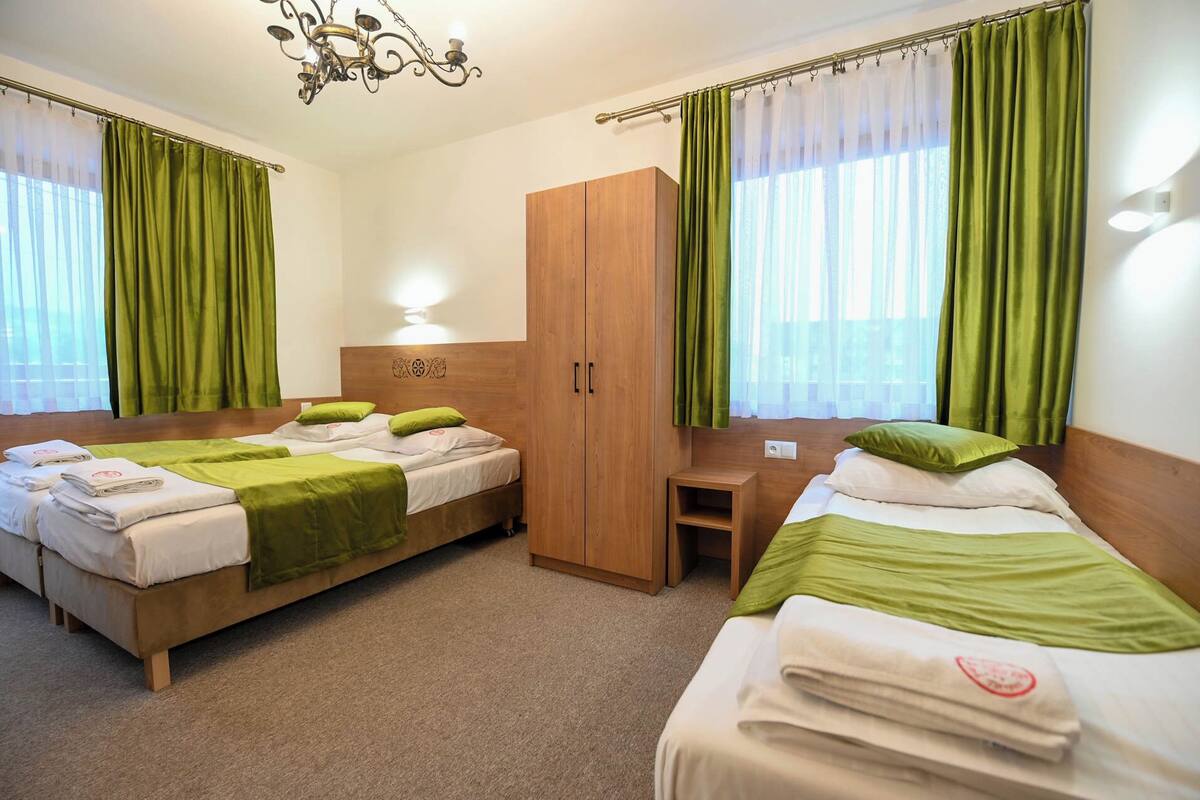 Habitación de hotel con dos camas, un armario, un escritorio y una araña.