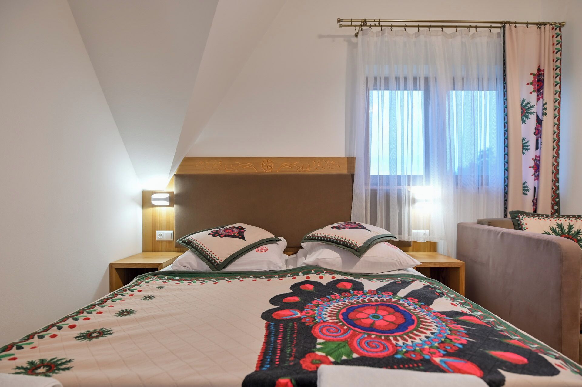 A bedroom with a bed, a nightstand, a lamp, and a window with curtains.