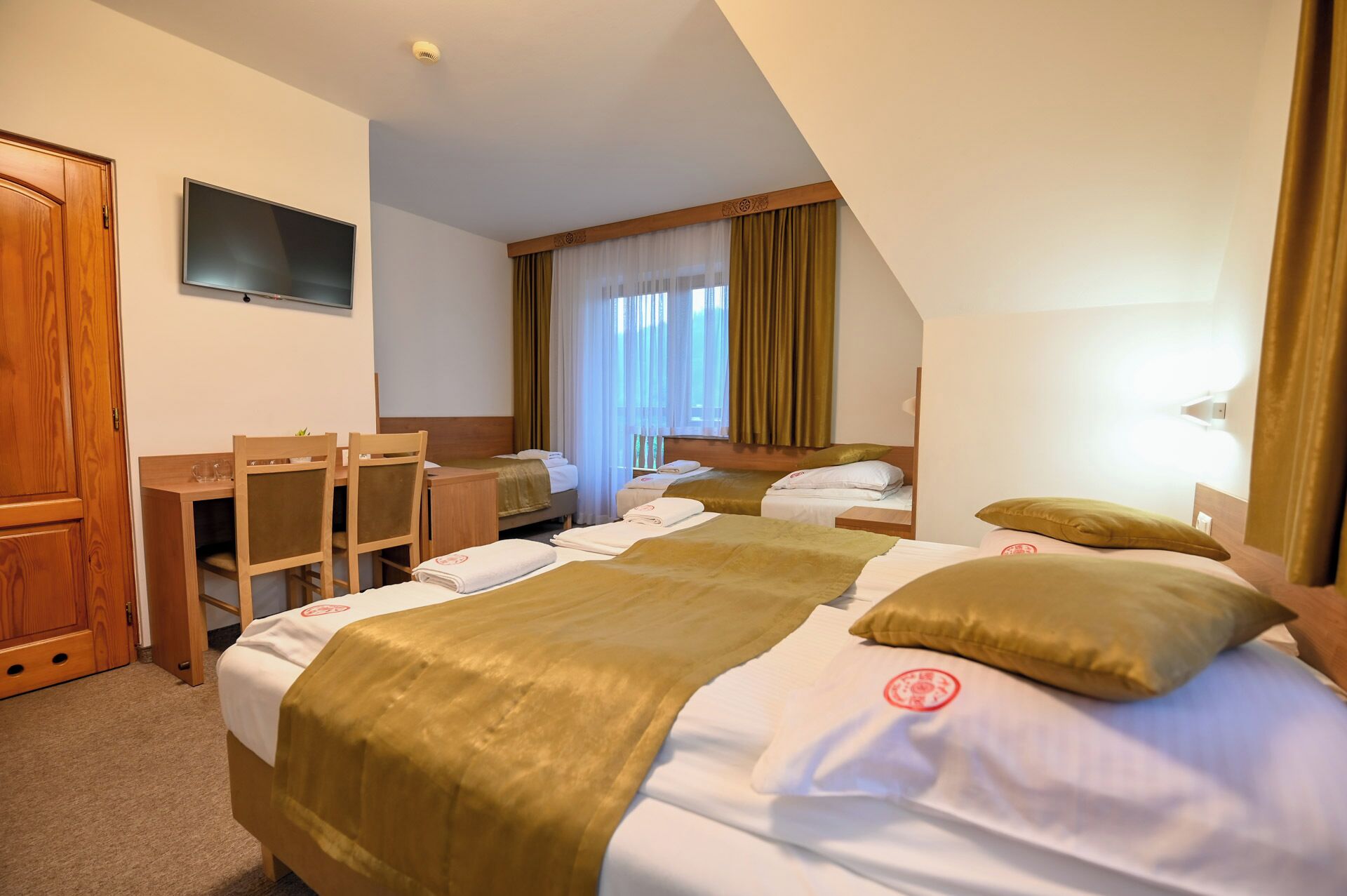 A hotel room with two beds, a desk, and a TV.