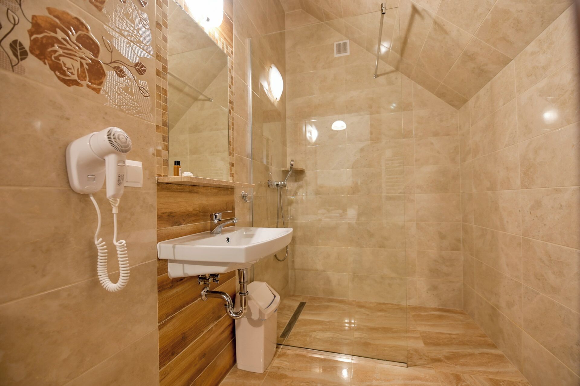 A bathroom with a shower, a sink, and a hairdryer mounted on the wall.