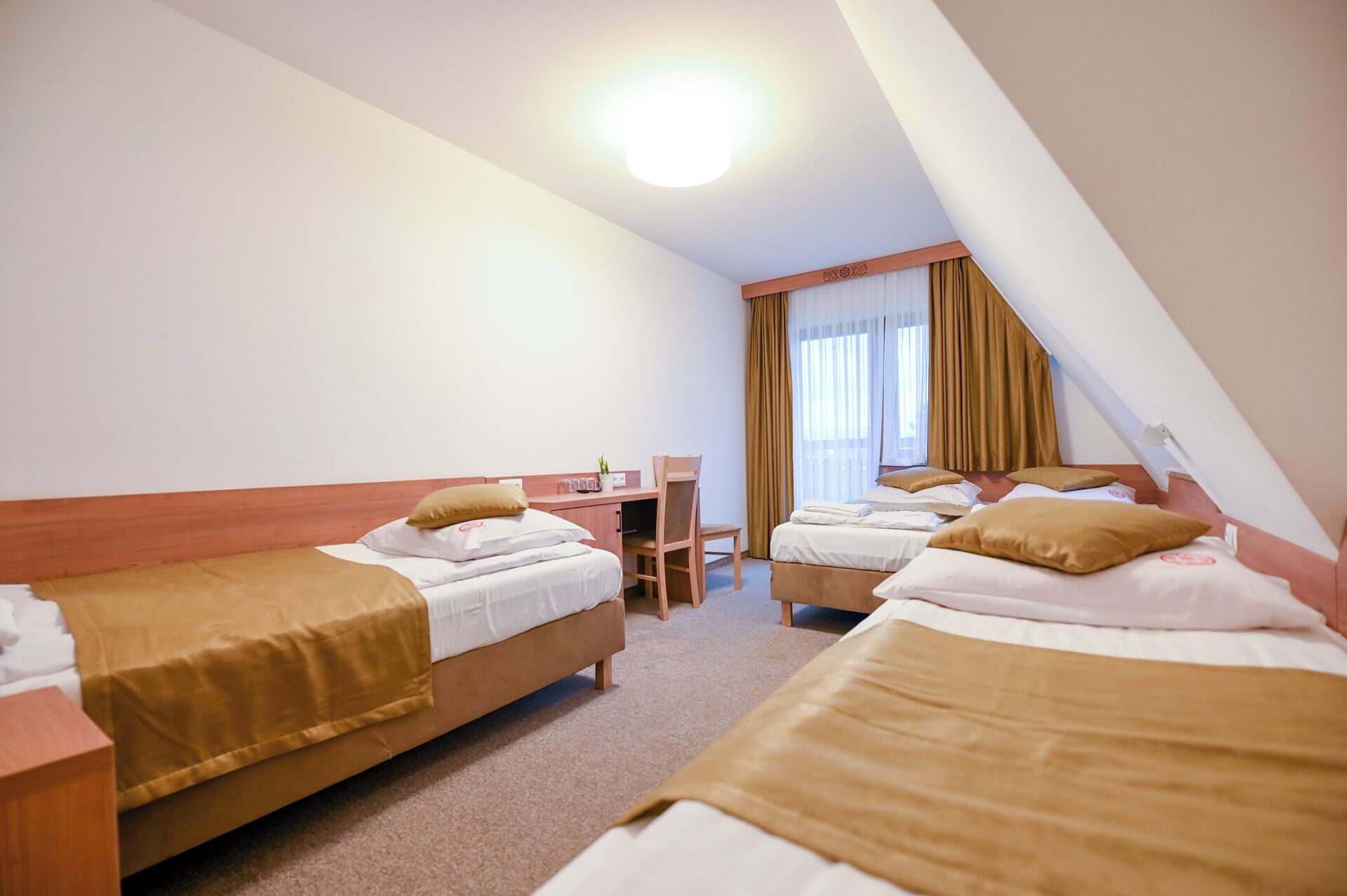 A hotel room with two beds, a desk, and a chair.
